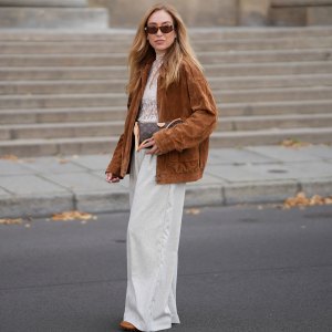BERLIN, GERMANY - SEPTEMBER 1: Sonia Lyson is seen wearing a white sheer lace high-neck blouse in a soft neutral tone from Baum und Pferdgarten; an oversized brown suede jacket with a relaxed cut and button details from Zara; Wide-leg light beige trousers that drape loosely and reach the floor from Munthe; Cogcnac-colored leather loafers with a classic, structured shape from Tods; a small brown and beige, monogram handbag with tan leather straps and details from Louis Vuitton; rectangular brown sunglasses with a modern shape from Givenchy; her blonde hair ist worn loose with a center part on September 1, 2025 in Berlin, Germany. Reformation Style Deals
