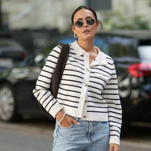 HAMBURG, GERMANY – AUGUST 17: Laura Noltemeyer is seen wearing a cream-and-navy striped knit cardigan with pearl buttons from Sézane; styled with light blue high-waisted straight-leg jeans with frayed hems from Zara; paired with taupe suede loafers from Birkenstock; is carrying a chocolate-brown woven leather shoulder bag from Les Visionnaires; accessorized with round metal-frame sunglasses from Persol and a delicate silver bracelet. Her hair is parted in the middle and styled in a sleek low ponytail on August 17, 2025 in Hamburg, Germany. (Photo by Moritz Scholz/Getty Images)