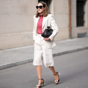 MUNICH, GERMANY - MARCH 27: Annette Weber is seen wearing a light beige tailored suit with a relaxed fit, consisting of a single breasted blazer and knee length tailored shorts from Max Mara; a red blouse with white polka dots and a soft high neckline from Glamometer and Seidensticker; black leather heeled sandals with a delicate ankle strap and bow detail from Ferragamo; a small black clutch bag with a textured leather finish from Max Mara; oversized black sunglasses with a bold frame from Gucci; her brown hair is worn loose with a natural finish and a center part on March 27, 2026 in Munich, Germany. (Photo by Moritz Scholz/Getty Images)