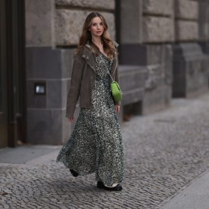 Anna Hiltrop seen wearing Boss green / beige / black print pattern pleated long dress, Boss brown suede leather jacket, Michael Kors green leather quilted crossbody bag and Gucci black leather laced boots, on February 16, 2024 in Berlin, Germany.