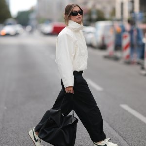 BERLIN, GERMANY - AUGUST 28: Sophia Geiss seen wearing an ivory COS windbreaker jacket with a high funnel neck and voluminous sleeves is paired with black COS wide-leg pleated trousers, white Nike x Jacquemus sneakers, a structured black COS leather bag and Mango sunglasses complete the look on August 28, 2026 in Berlin, Germany. (Photo by Jeremy Moeller/Getty Images)