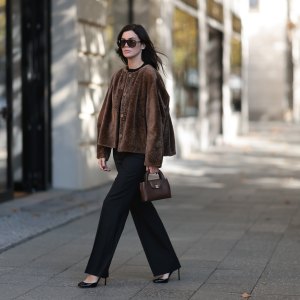 BERLIN, GERMANY - OCTOBER 5: Leo Eberlin seen wearing Tom Ford oversized black sunglasses with dark lenses, Manzoni 24 chocolate brown shearling jacket with a relaxed boxy silhouette and tonal button fastening, Zara fitted black crew-neck top, Leo Mathild diamond jewelry including stud earrings and statement rings, Audemars Piguet yellow gold watch, Chanel structured brown leather top-handle bag with gold-tone CC hardware, Sézane black tailored flared trousers with a clean high-waisted silhouette, Tom Ford black patent leather heels on October 5, 2026 in Berlin, Germany. (Photo by Jeremy Moeller/Getty Images)