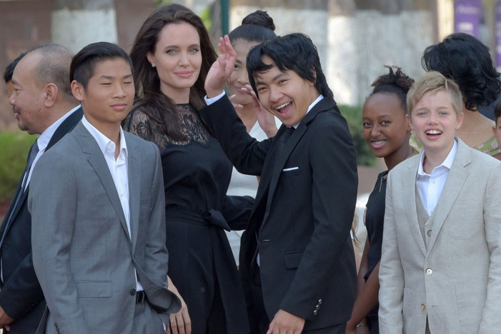 Hollywood star Angelina Jolie (3rd L) and her children including Maddox Jolie-Pitt (C) gesture to media in front of the royal residence for a meeting with Cambodian King Norodom Sihamoni in Siem Reap on February 18, 2017