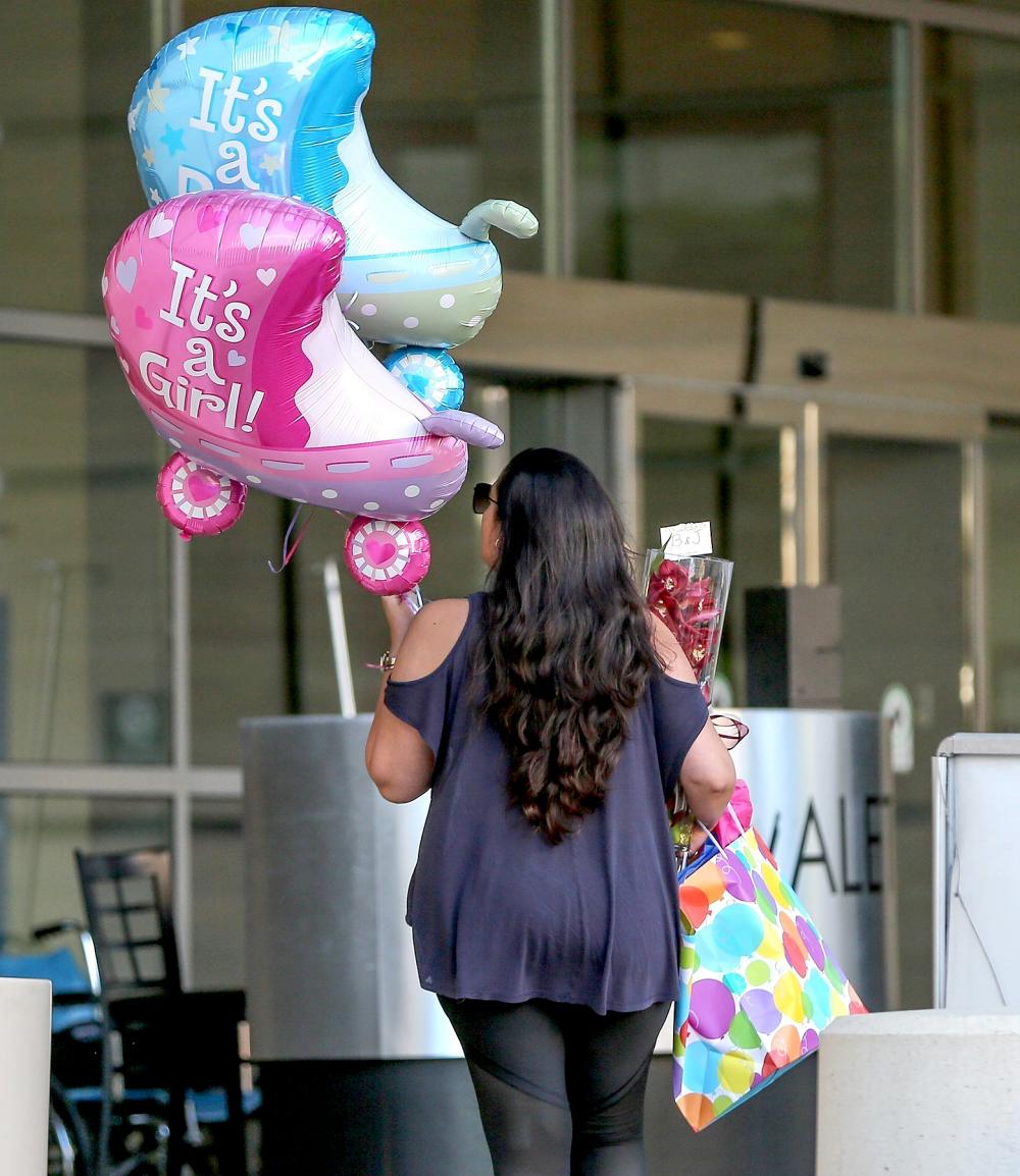 A woman is seen heading into the hospital holding balloons welcoming a girl and a boy, along with flowers, a gift bag, and a card that reads "B & J," on June 17, 2017.