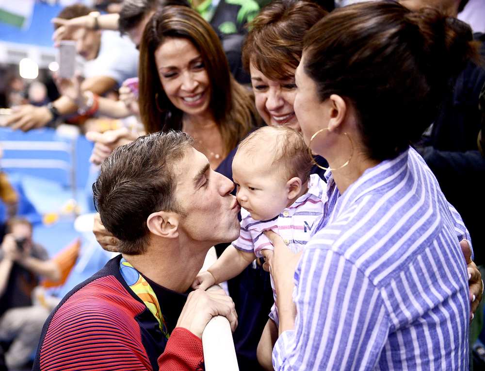 USA's Michael Phelps kisses his son, Boomer, next to his fiancée, Nicole Johnson (R) and mother Deborah (C) after he won the men's 200-meter butterfly final at the Rio 2016 Olympic Games at the Olympic Aquatics Stadium in Rio de Janeiro on August 9, 2016.