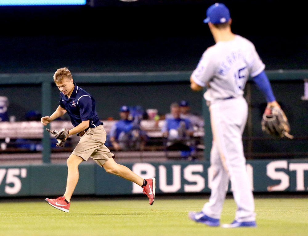 A grounds keeper retrieves a small cat that ran across the outfield in the sixth inning of a game between the St. Louis Cardinals and the Kansas City Royals on Wednesday, Aug. 9, 2017, at Busch Stadium in St. Louis.