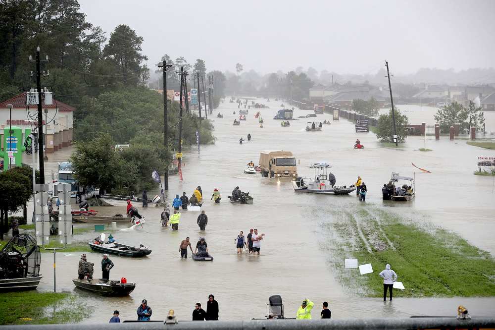 People walk down a flooded street as they evacuate their homes after the area was inundated with flooding from Hurricane Harvey on August 28, 2017 in Houston, Texas.