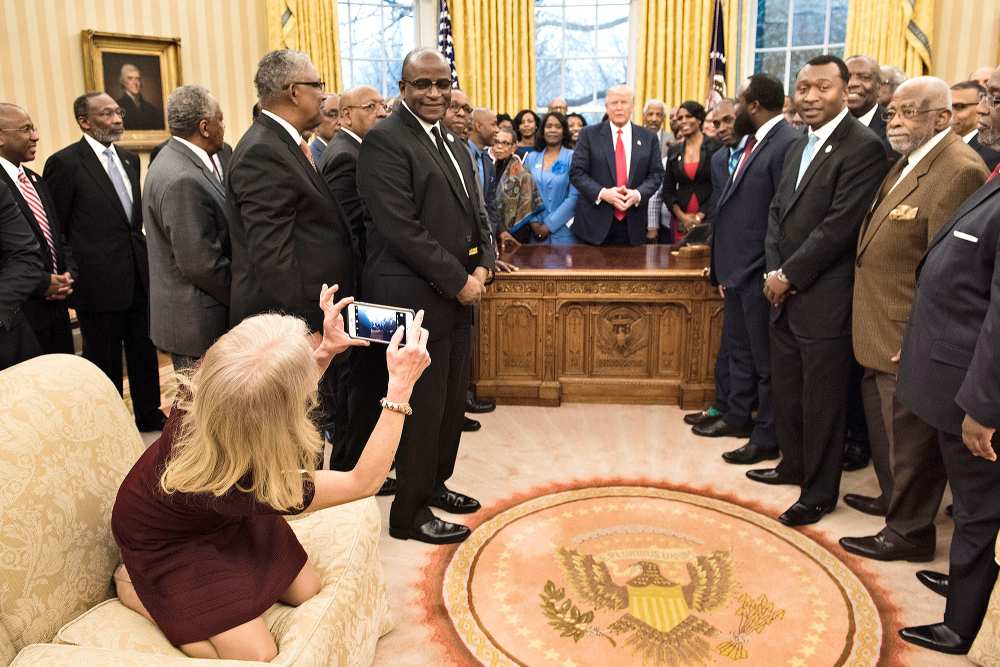 Counselor to the President Kellyanne Conway takes a photo as US President Donald Trump and leaders of historically black universities and colleges talk before a group photo in the Oval Office