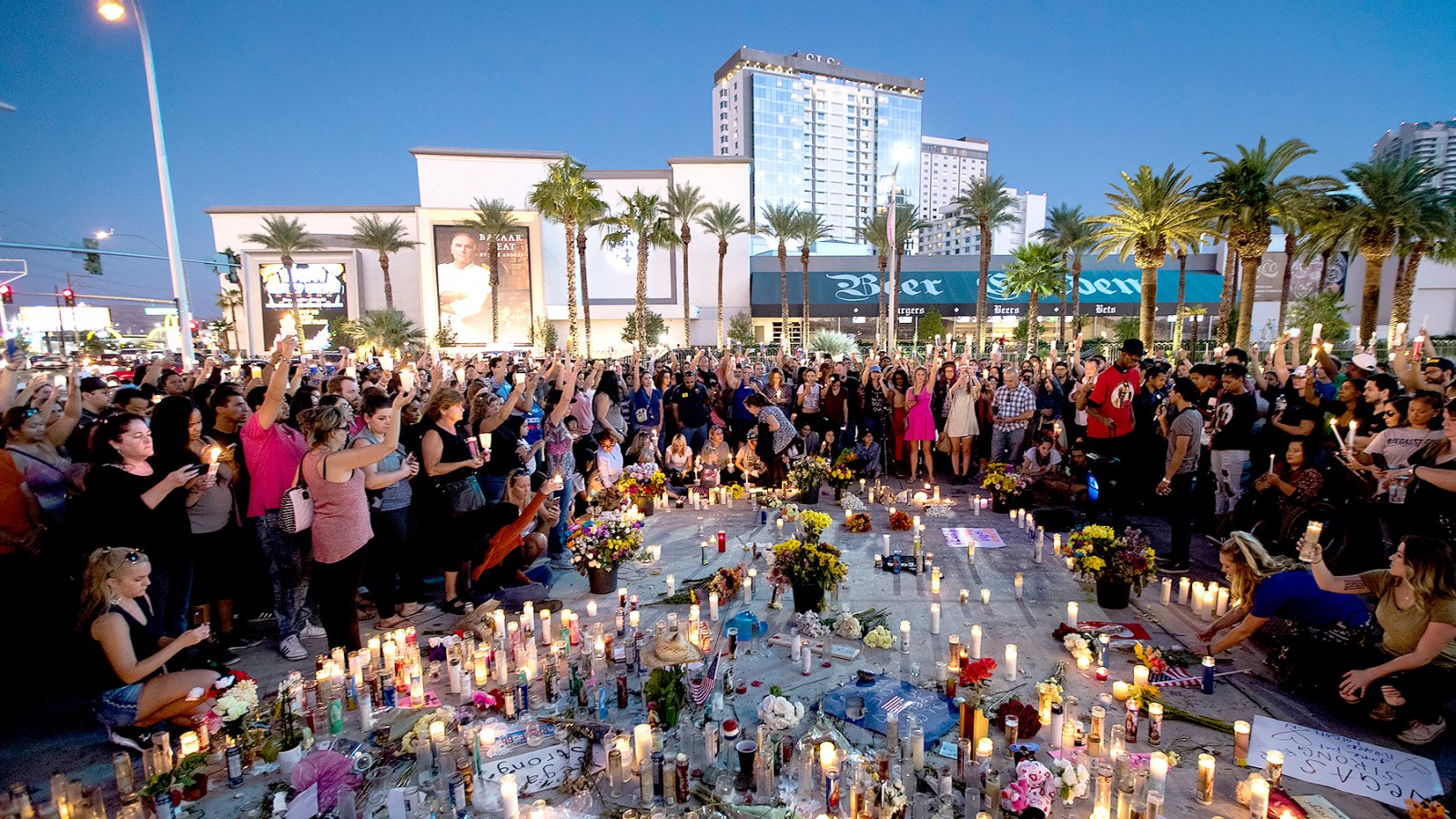 Mourners hold their candles in the air during a moment of silence during a vigil to mark one week since the mass shooting at the Route 91 Harvest country music festival, on the corner of Sahara Avenue and Las Vegas Boulevard at the north end of the Las Vegas Strip, on October 8, 2017 in Las Vegas, Nevada.