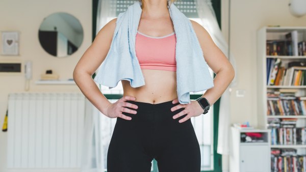 Mid section of young woman training, standing with hands on hips