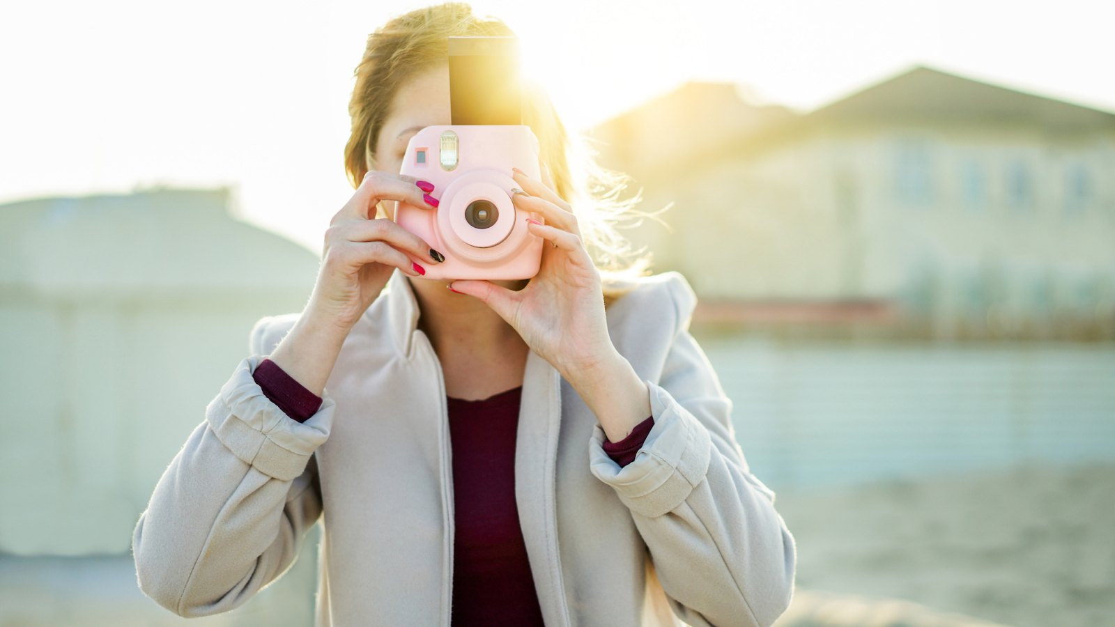 Woman Holding Instant Camera While Standing At Beach