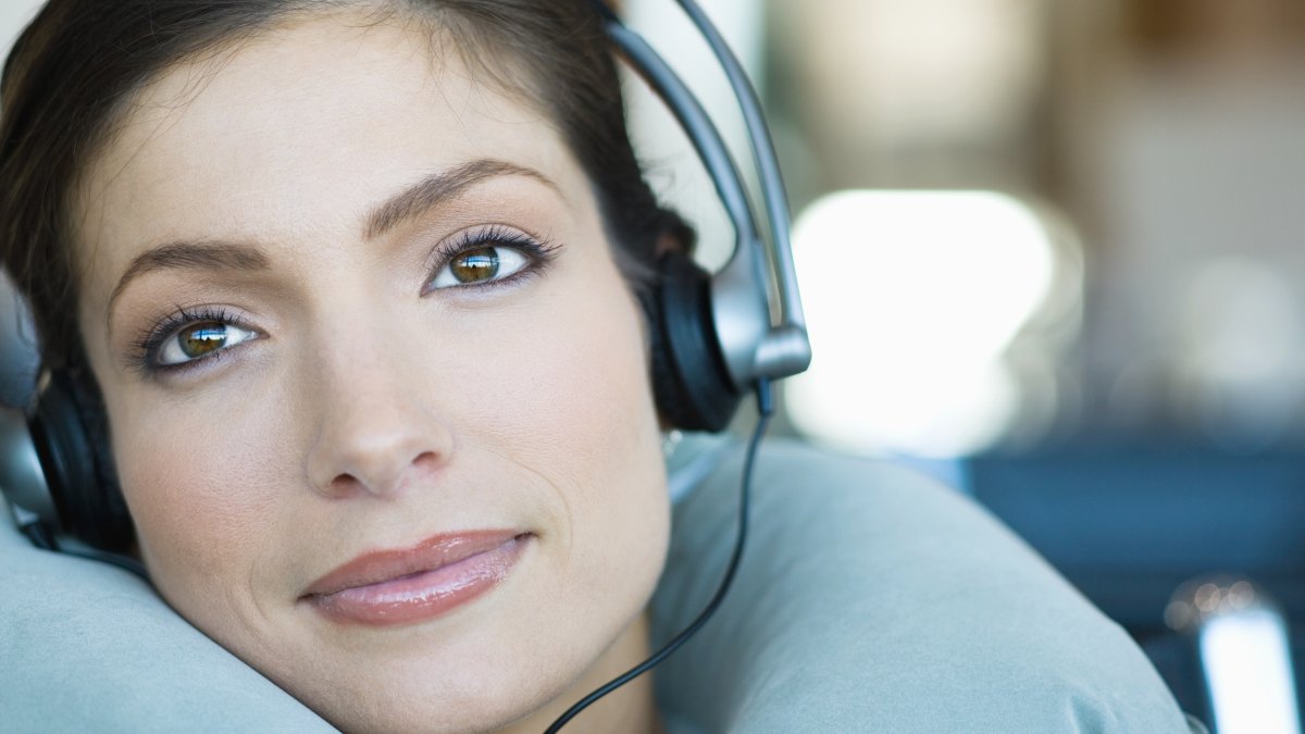 Woman wearing headphones and using neck pillow