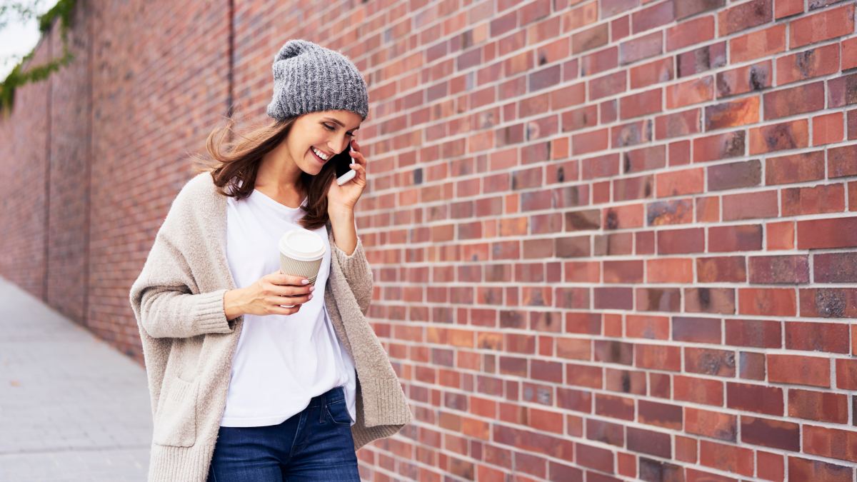 Happy woman with coffee to go on the phone