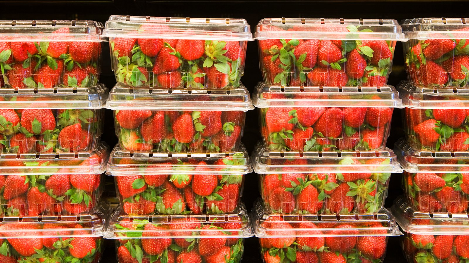 Strawberries in containers on supermarket shelf.