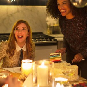 Laughing friends enjoying cake at candlelight Christmas dinner party
