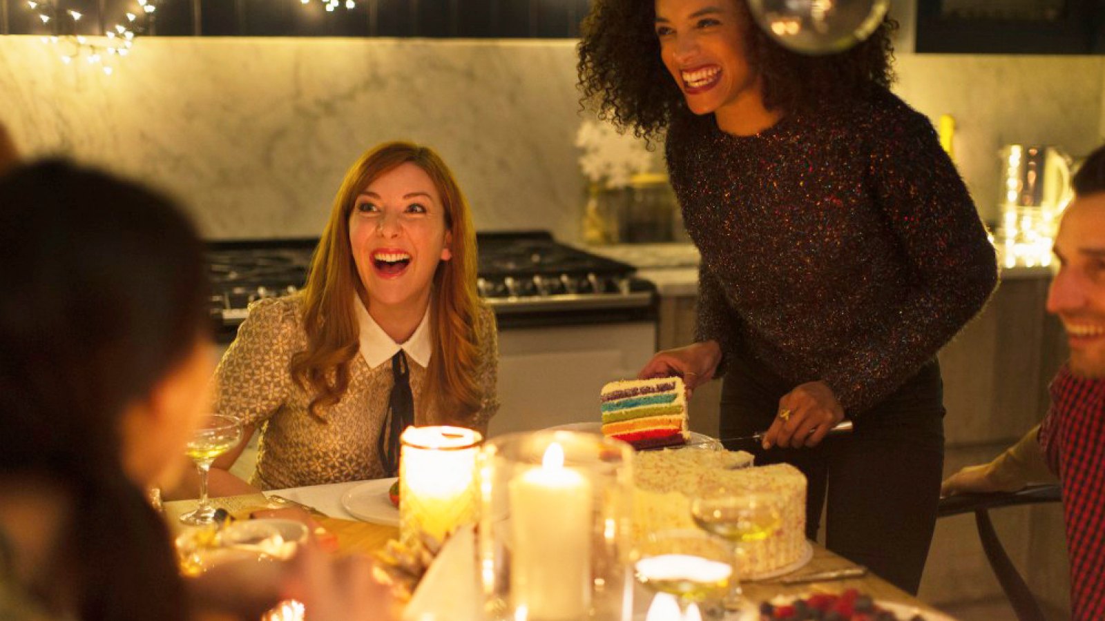 Laughing friends enjoying cake at candlelight Christmas dinner party