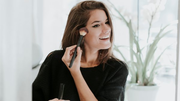 Mirror image of young woman applying Makeup