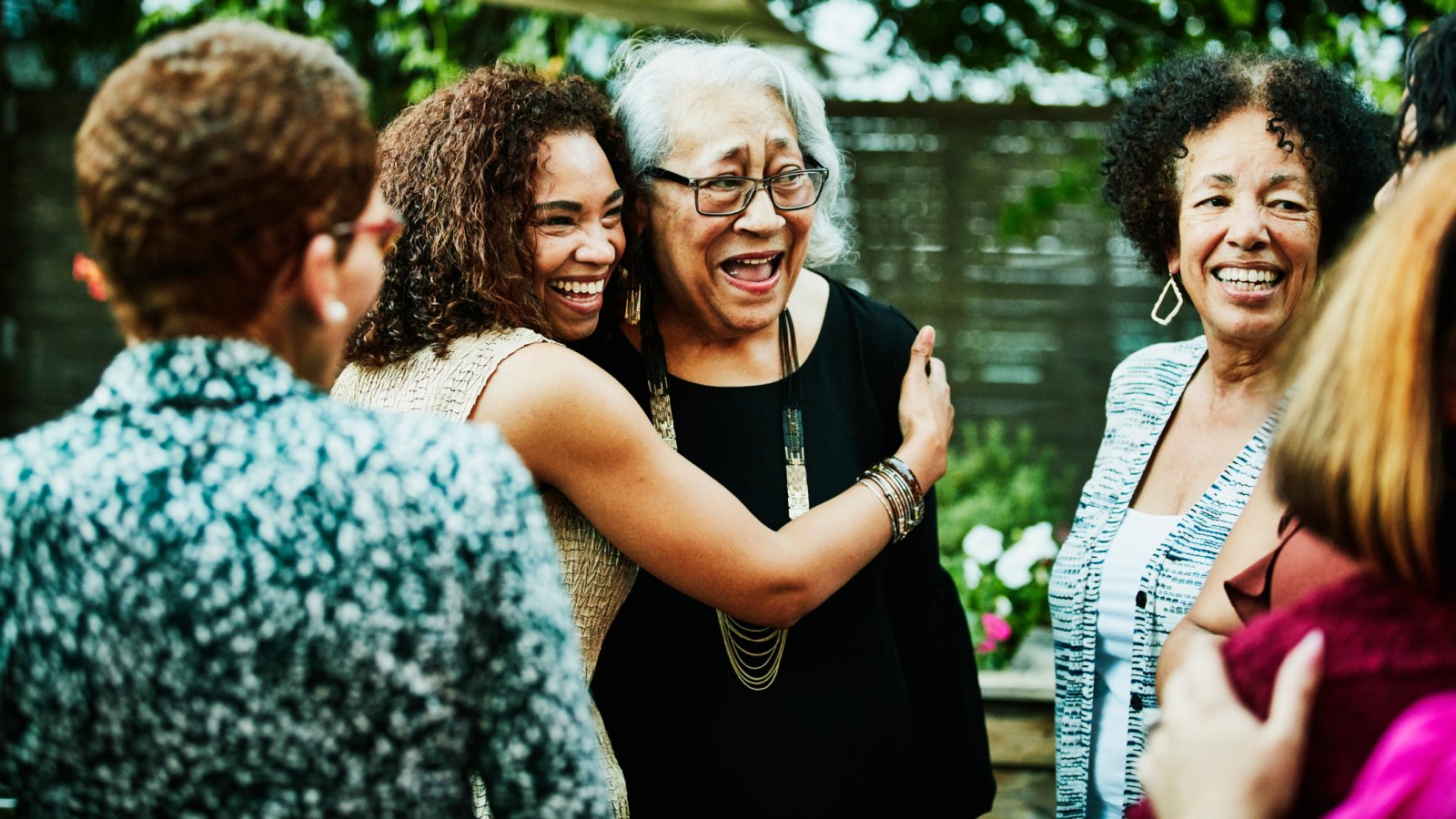 Mature daughter embracing senior mother after outdoor family dinner party