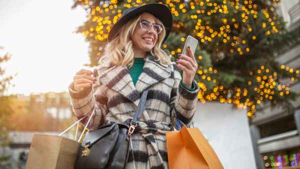 Carefree woman shopping downtown andusing mobile phone