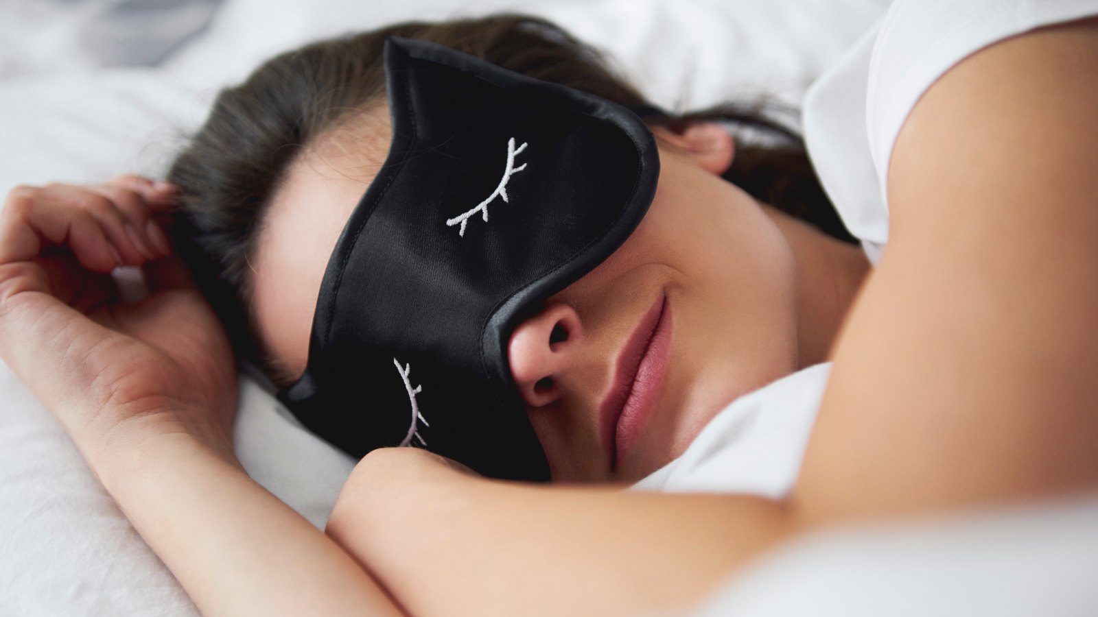 Portrait of young woman with sleep mask in bed