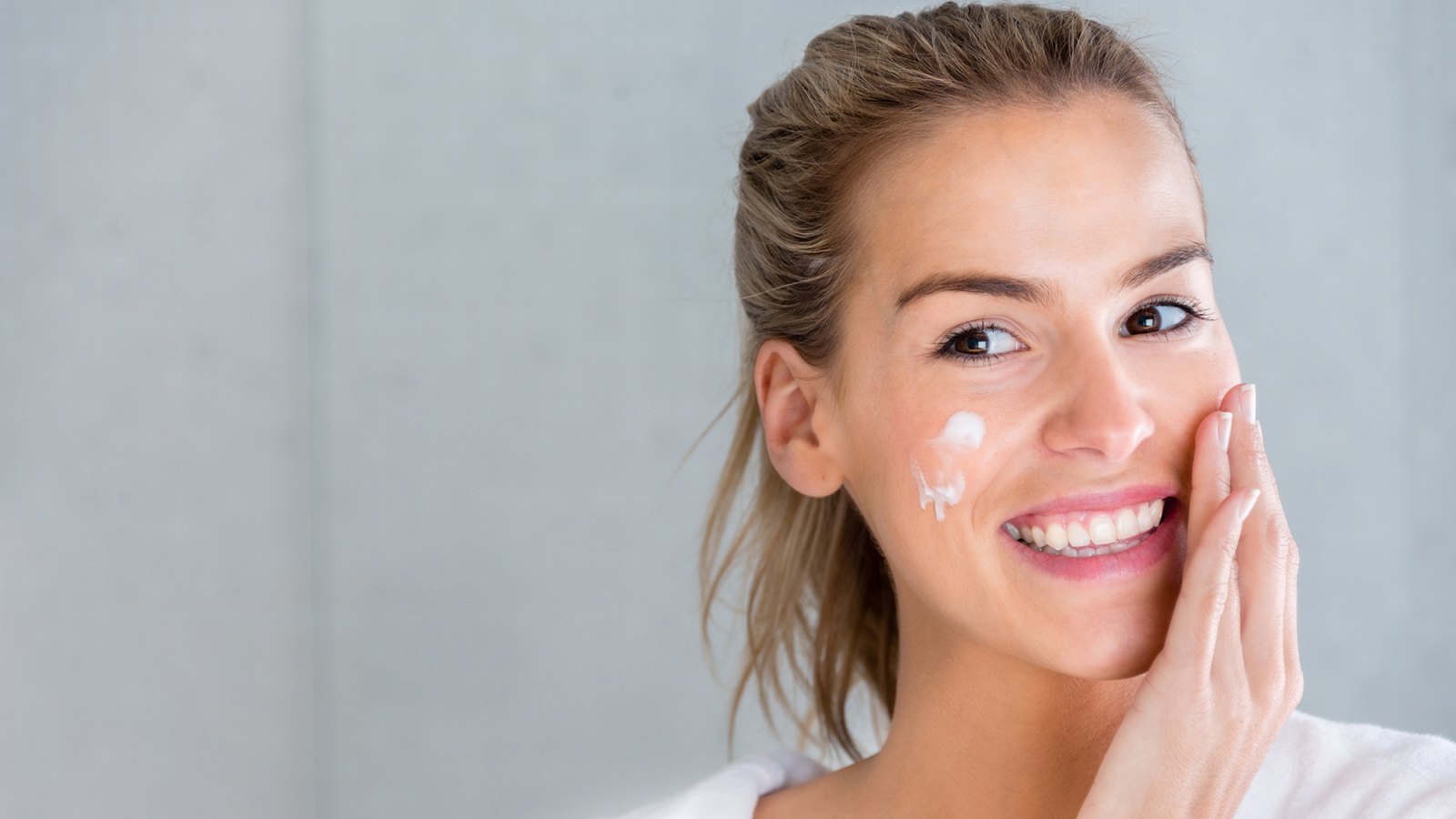 Beauty portrait of a woman using moisturising cream