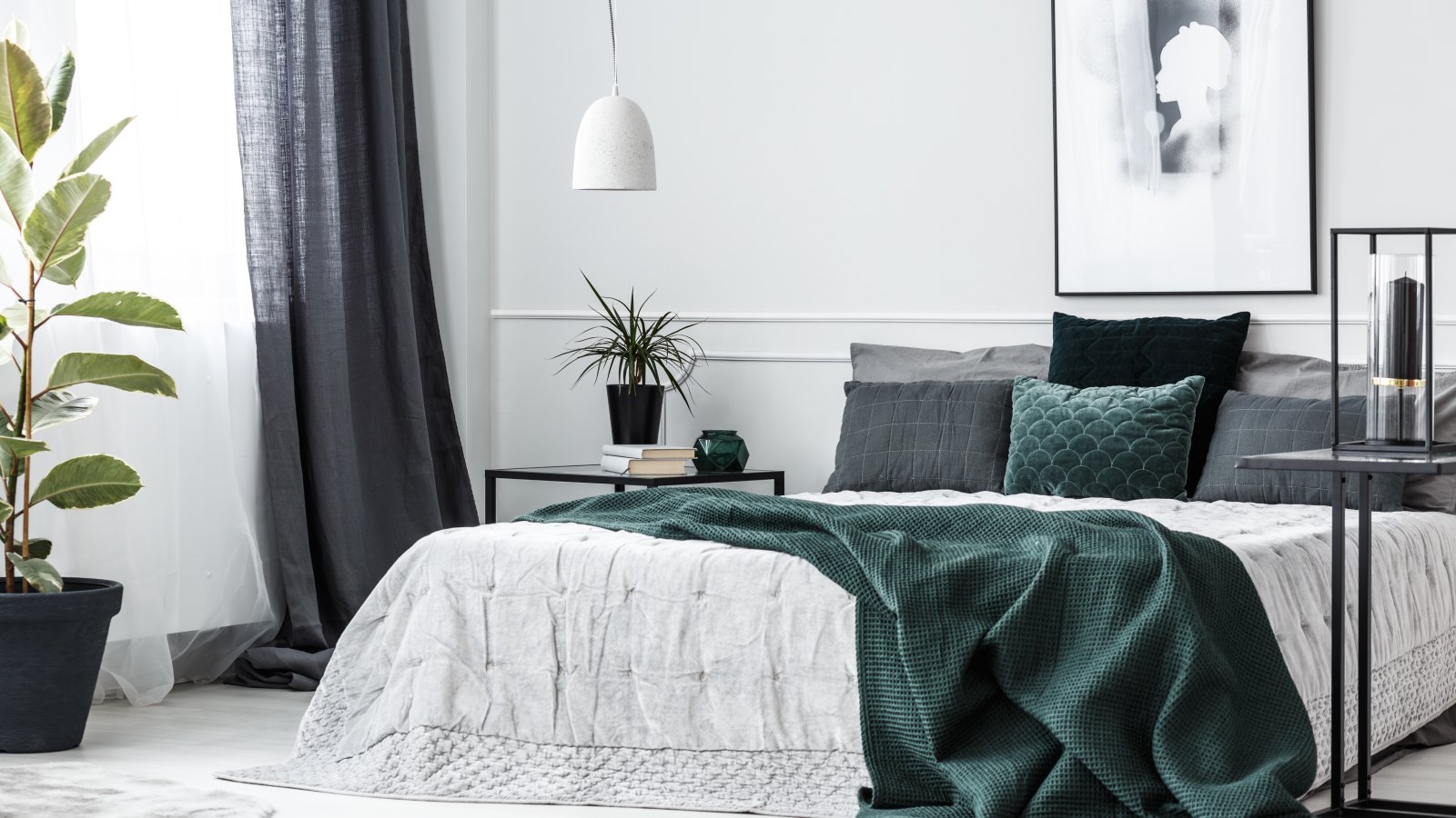 Green blanket on bed in elegant bedroom interior with poster on white wall and plant on table