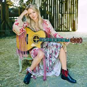 Jewel Holding Guitar in Dress Sitting in a Barn With Hay on the Floor