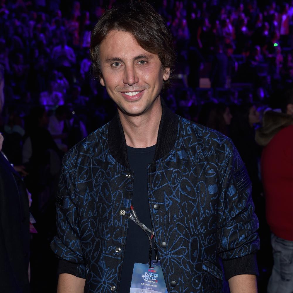 Jonathan Cheban attends Jingle Ball in a black jacket with a blue pattern on it.