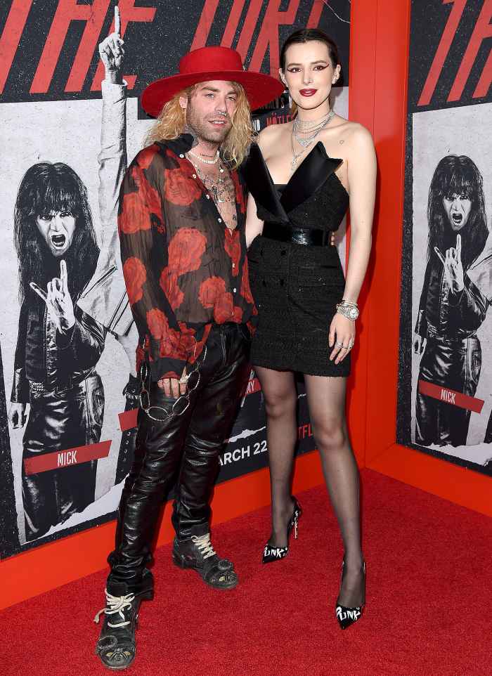 Mod Sun Wearing Black Leather Pants and Red Shirt with Red Brim Hat and Bella Thorne Wearing Black Dress