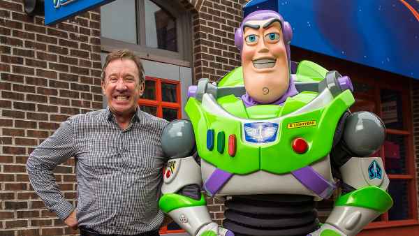 Tim Allen Poses With His Hands on His Hips Next To Buzz Lightyear With A Giant Grin