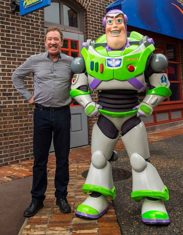 Tim Allen Poses With His Hands on His Hips Next To Buzz Lightyear With A Giant Grin