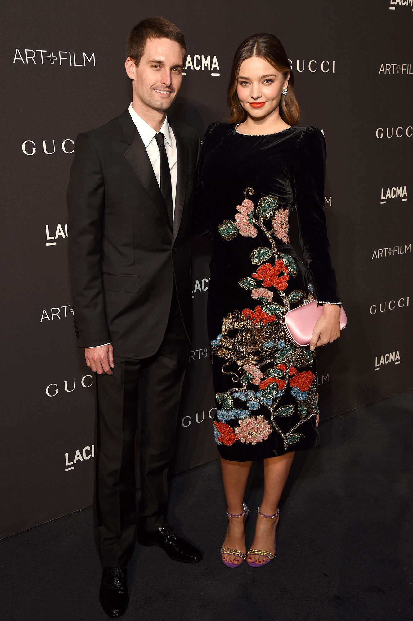 Evan Spiegel and Miranda Kerr Inside Pregnant Life Black Suit Black Dress WIth Flowers and Pink Hand Bag Purse