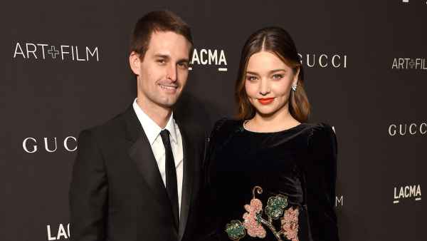 Evan Spiegel and Miranda Kerr Inside Pregnant Life Black Suit Black Dress WIth Flowers and Pink Hand Bag Purse