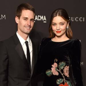 Evan Spiegel and Miranda Kerr Inside Pregnant Life Black Suit Black Dress WIth Flowers and Pink Hand Bag Purse