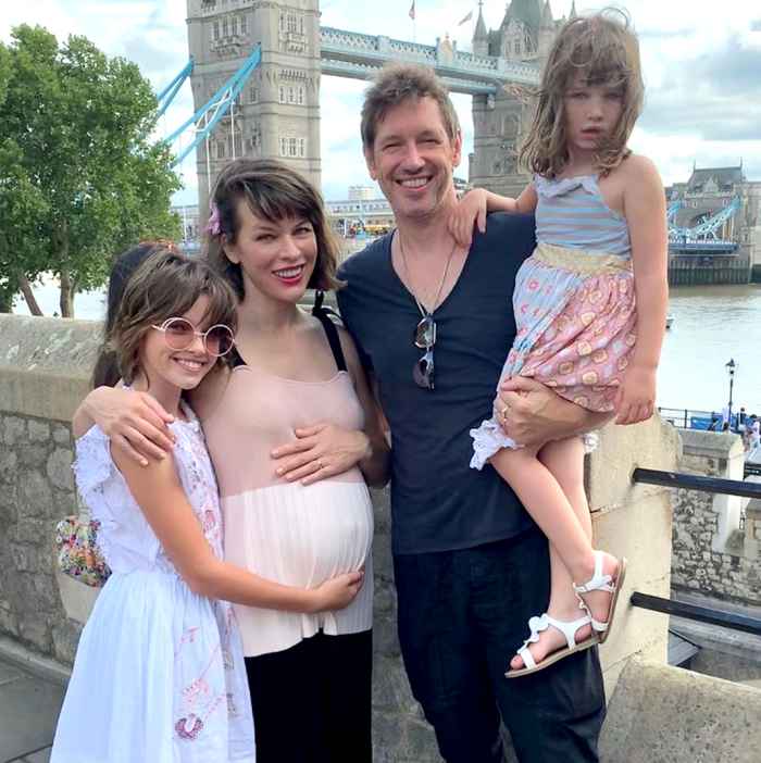 Milla-Jovovich-Cradles-Growing-Baby-Bump-in-Sweet-Family-Pic-With-Husband-and-Daughters