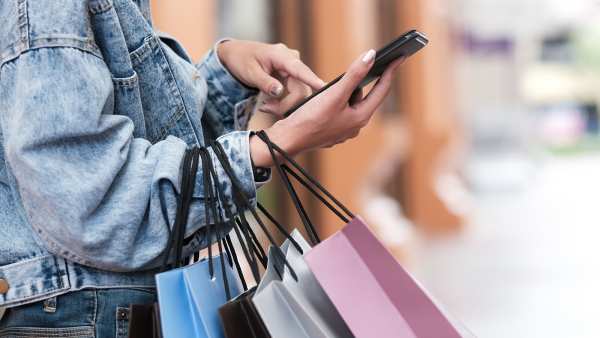 Closeup woman hand using mobile phone in shopping checking sales promotion.