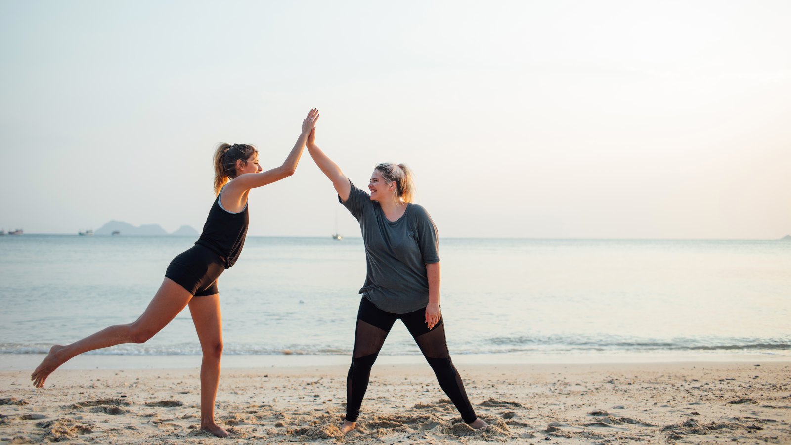 Two beautiful girls working out together on the beach