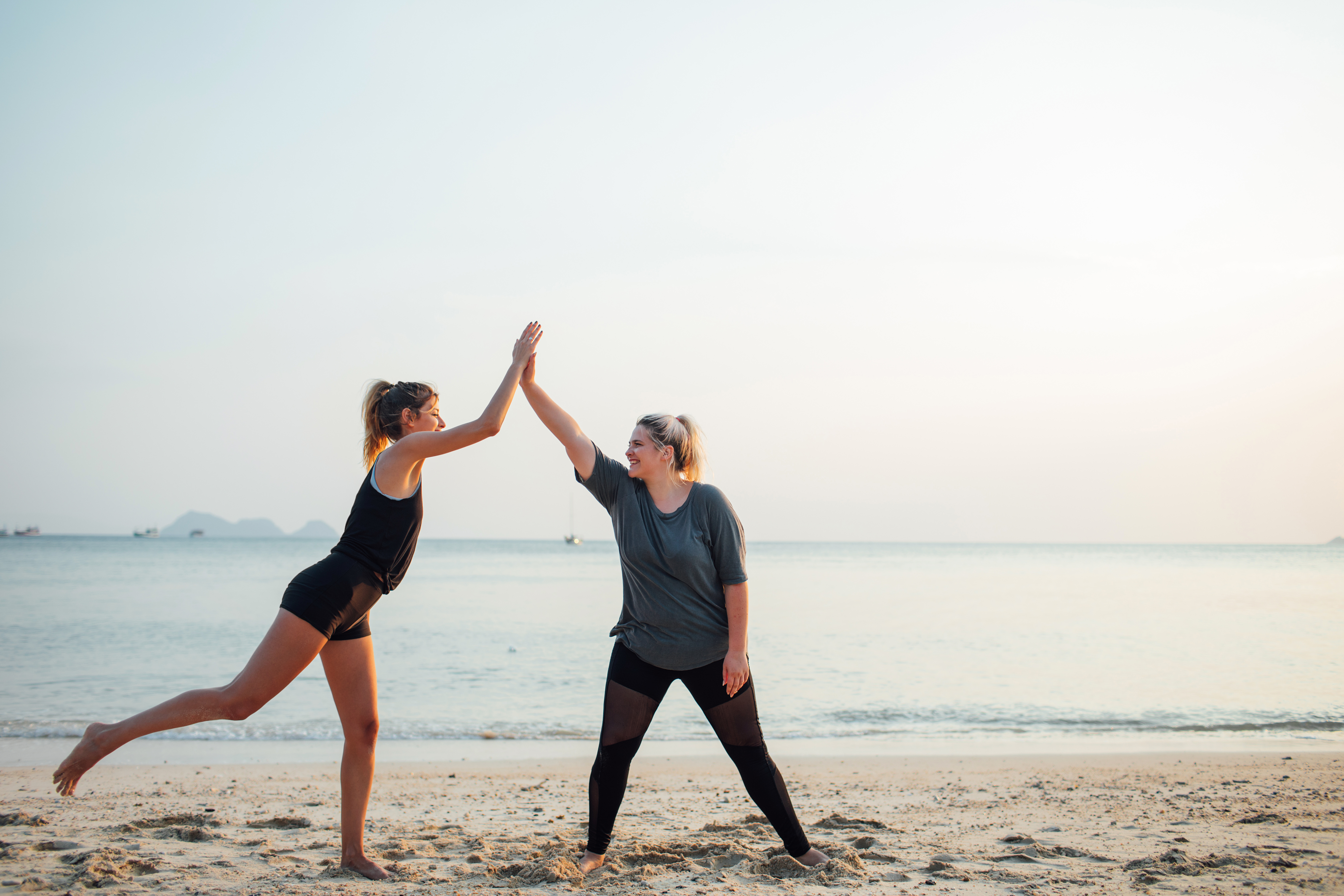 Two beautiful girls working out together on the beach