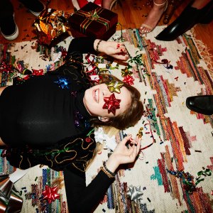 Laughing woman lying on floor with bows over eyes during holiday party with friends