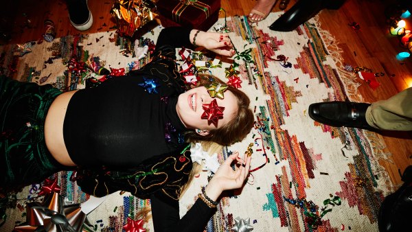 Laughing woman lying on floor with bows over eyes during holiday party with friends