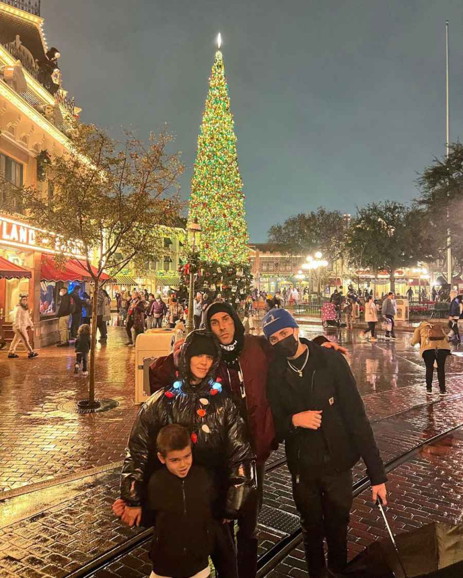 Kourtney Kardashian, Travis Barker, Landon and Reign pose in front of a Christmas tree.