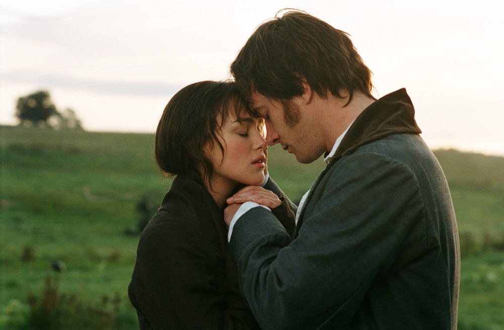 A man and woman stand closely in an embrace in a serene meadow at sunrise. They touch foreheads tenderly, eyes closed, expressing deep emotion.