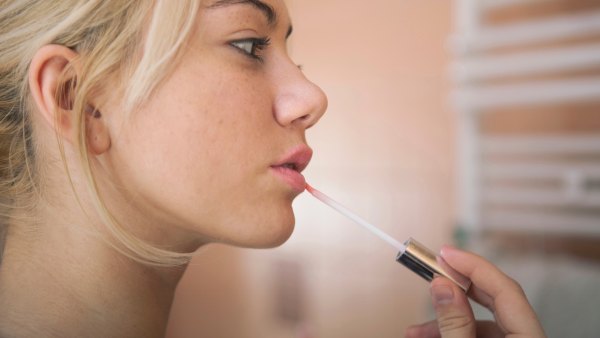 Woman-Applying-Lip-Gloss-Stock-Photo
