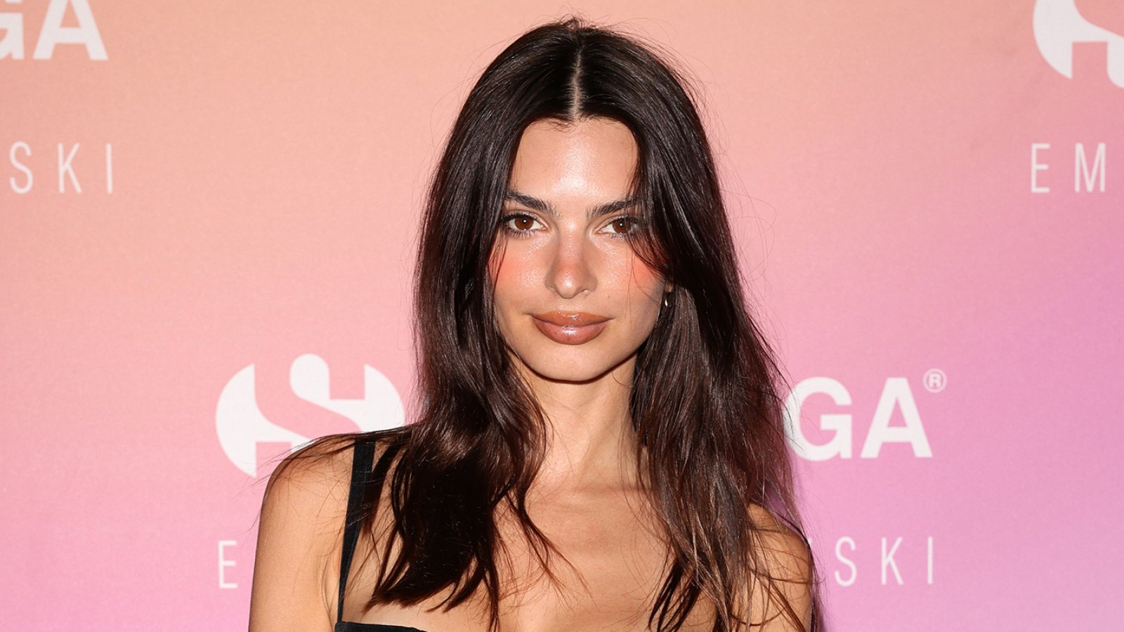 Emily Ratajkowski Wears Black Dress and Poses in front of a pastel gradient backdrop red carpet for the Superga Party in Florence, Italy