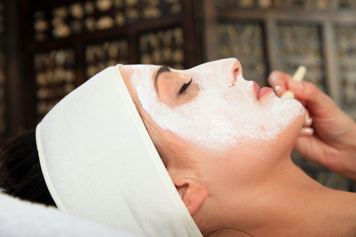 A woman getting a facial uses an ice roller
