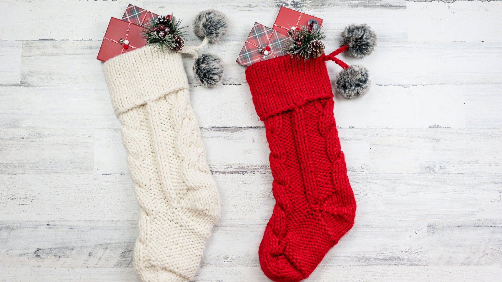 Two knitted Christmas stockings on distressed wood background