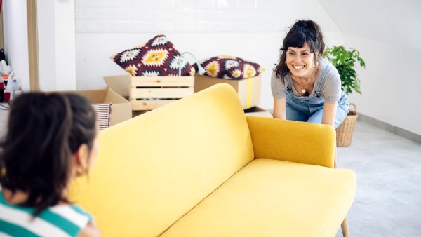 Happy twin sisters bringing the new furniture while moving into a new home.