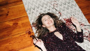 Happy young woman in glittering cocktail dress on carpet floor, flash light, user generated content
