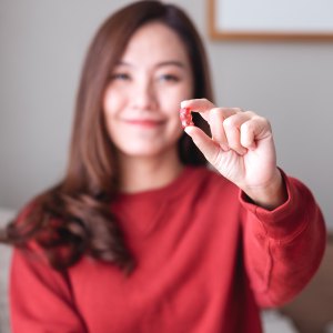 Closeup image of a young woman holding and looking at a red jelly gummy bears