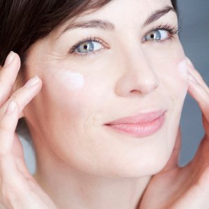 Woman applying cream on her face.
